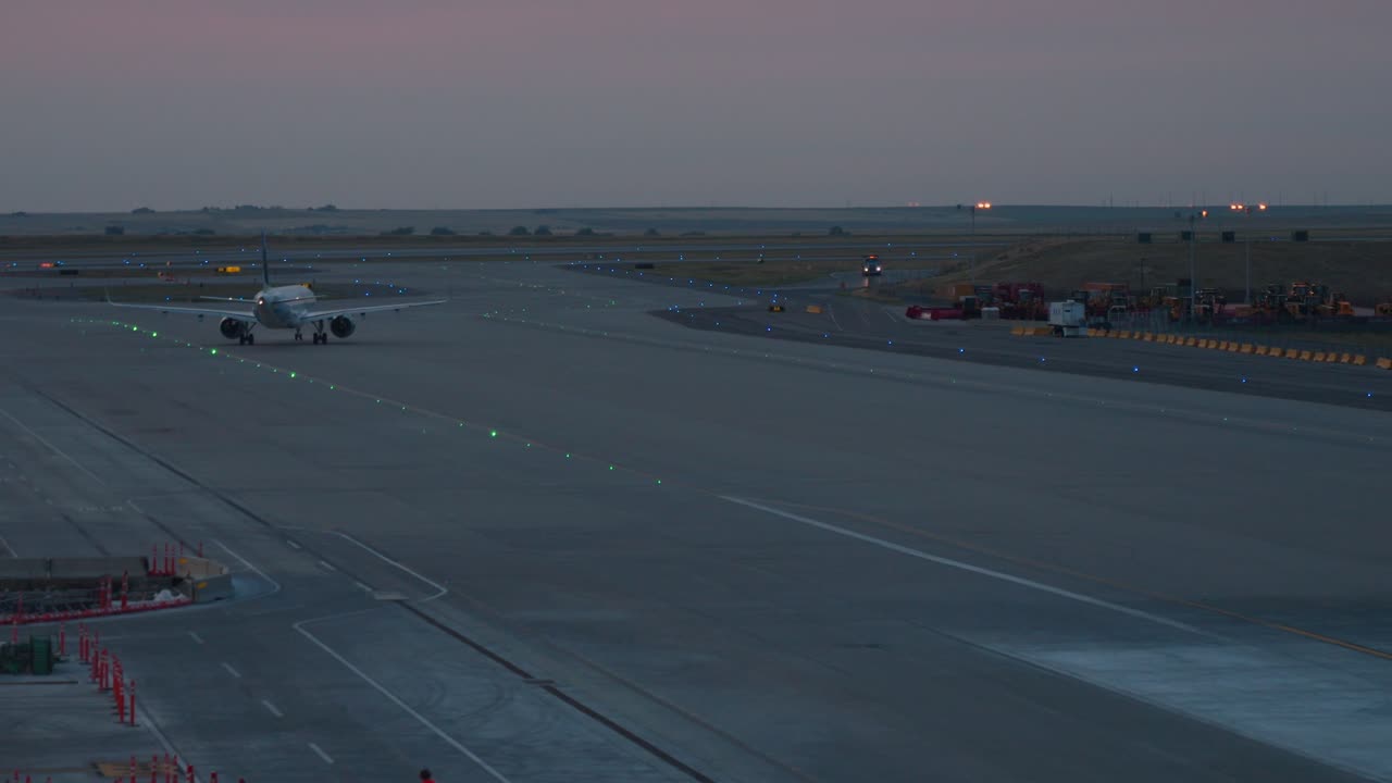 A large jet airliner slowly pulling away from the departure gate at dawn at Denver International Airport. Gentle sunrise in the background