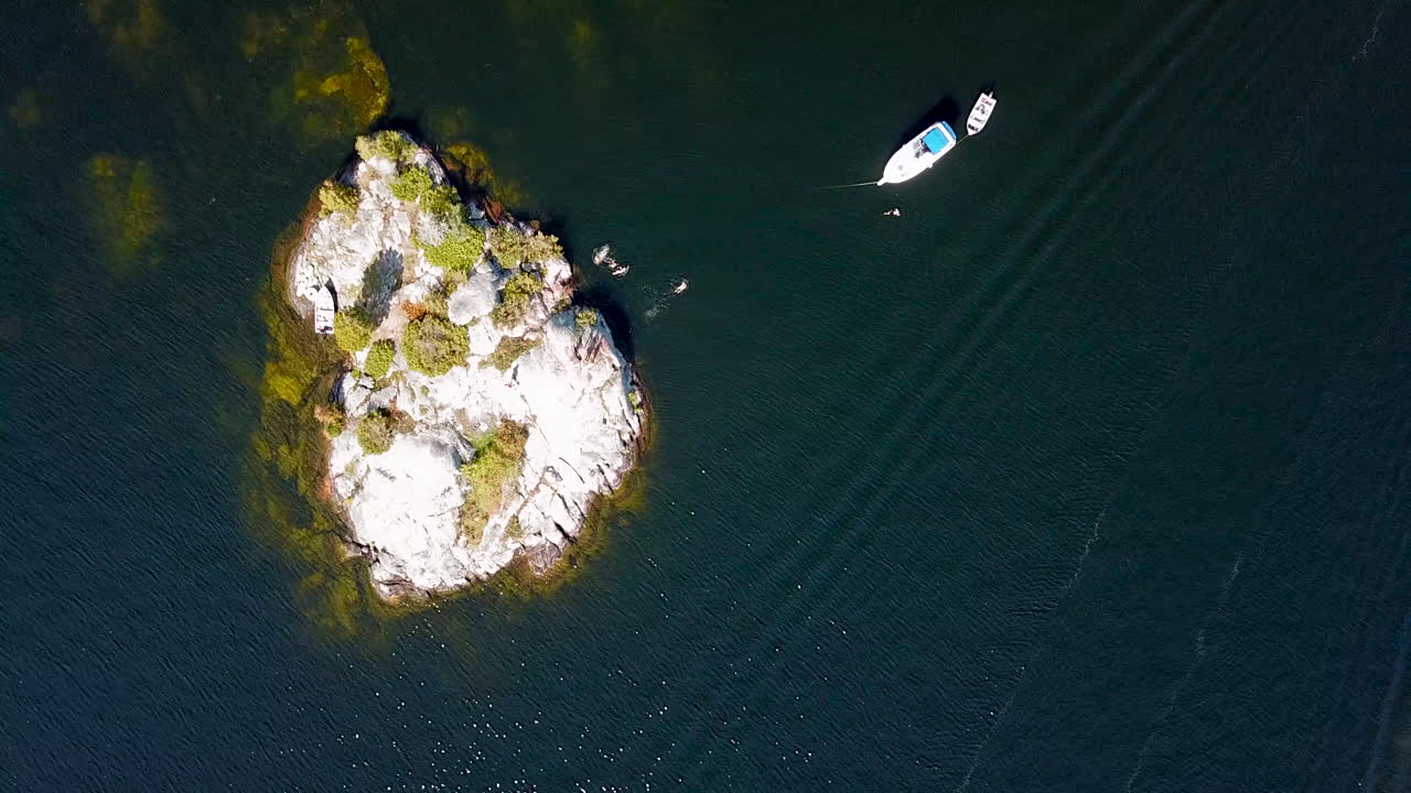 toma aérea de 4k de personas nadando en una isla rocosa