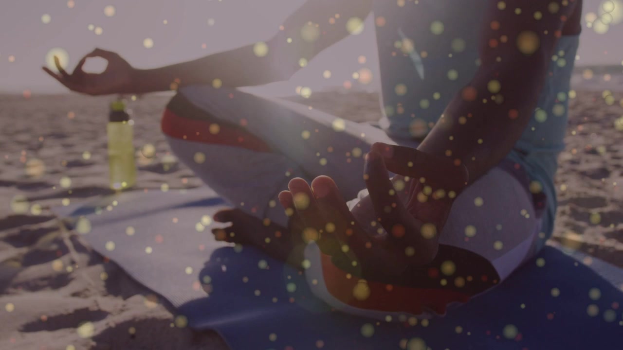 Vertical video: At sunrise man sitting on beach breathing for wellness while gold bokeh framing mat