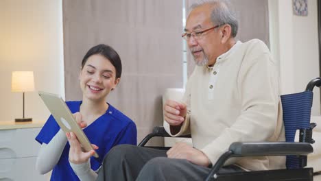 asian senior elderly male patient talking to physician nurse at nursing home care. caregiver doctor explain diagnosis and medical treatment plan to older disabled guy on wheelchair in a health clinic.