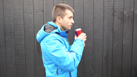 man drinking hot coffee from a thermos to get warm on a black background