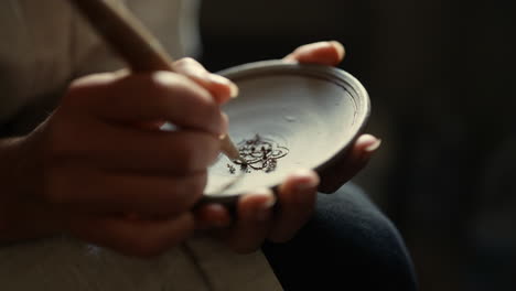 Unknown-ceramist-making-ornament-on-plate-in-studio.-Girl-working-with-wet-clay