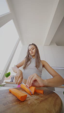 young woman cutting carrots in a kitchen