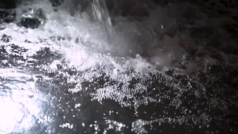 stream of water splashing into clear illuminated pool