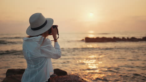 mujer tomando una foto al atardecer en la playa