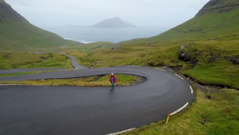 Aerial-pullback-shot-of-a-lonely-woman-walking-on-Nordradalsskard-Street