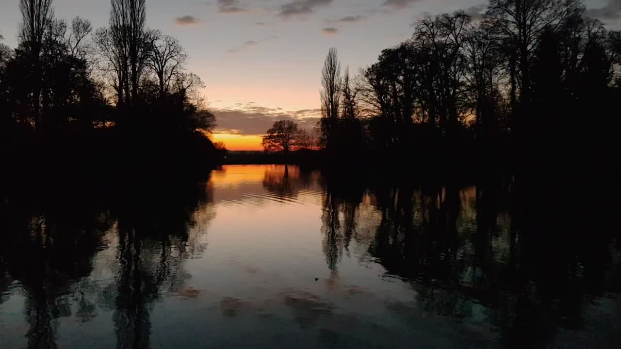 Panorama view of sunset with reflection on lake and birds flying through shot