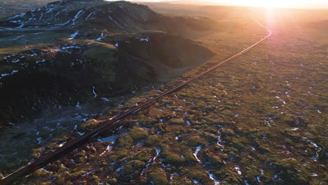 drone captures vast, snowy landscape during dramatic sunset in iceland, with vibrant hues of orange sunlight and casting warm glow over pristine land, creating breathtaking scene