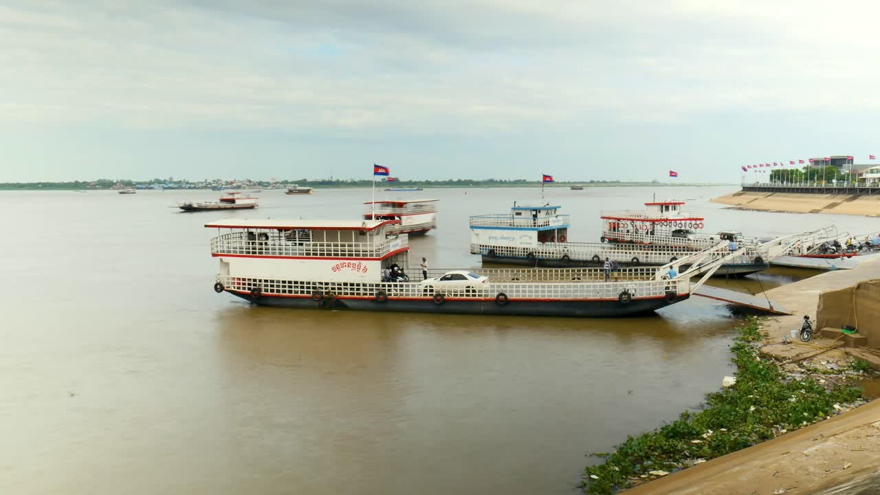 Cars offload from ferry in Cambodia's Mekong River transporting people at midday