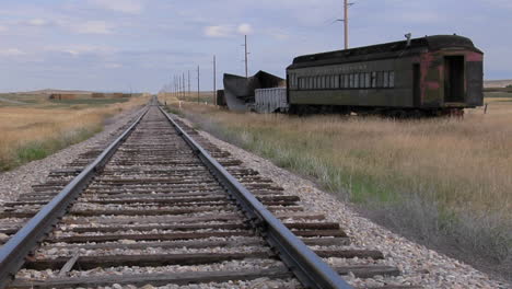 an old abandoned pullman railway car sits on a siding along a lonely stretch of railroad track