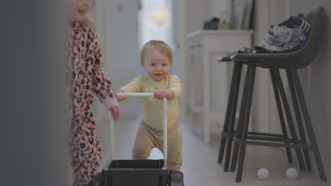 girl child and baby boy walking indoors towards camera