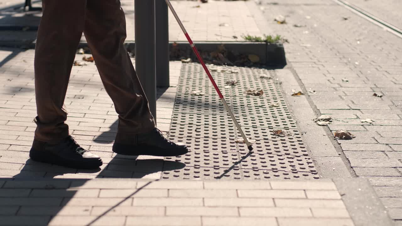 hombre con discapacidad visual está caminando en una baldosa de advertencia táctil con la ayuda de su bastón. superficie de advertencia detectable para los discapacitados visuales al aire libre en la ciudad.