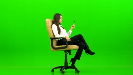 la hermosa mujer en la silla de la oficina hablando en el fondo verde