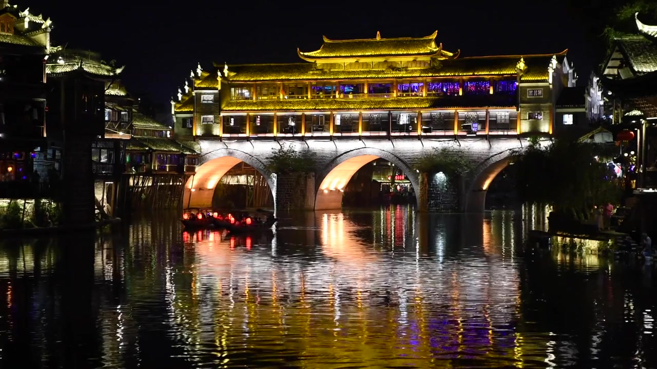 Vista noturna da Cidade Antiga de Fenghuang na Província de Hunan, China, destacando seu encanto histórico com arquitetura chinesa tradicional, casas sobre palafitas, ruas de paralelepípedos e paisagens ribeirinhas.