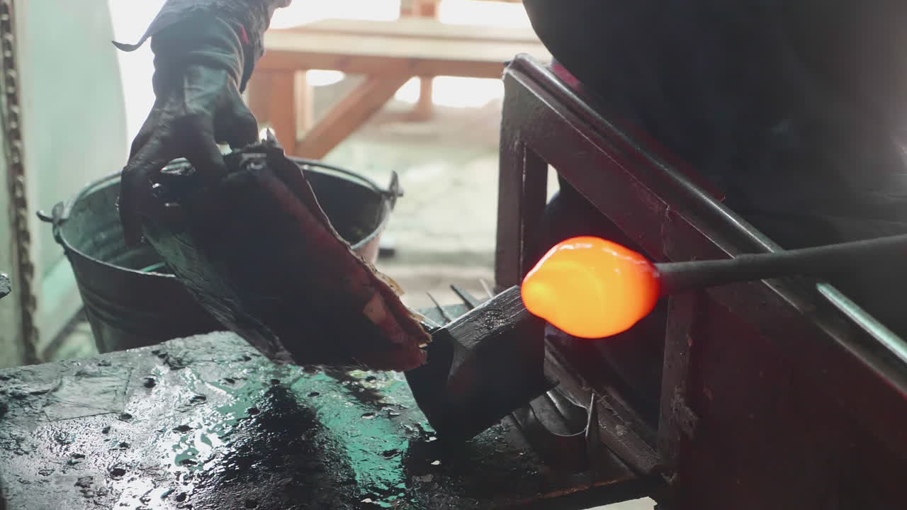 A man molding hot glass while seated