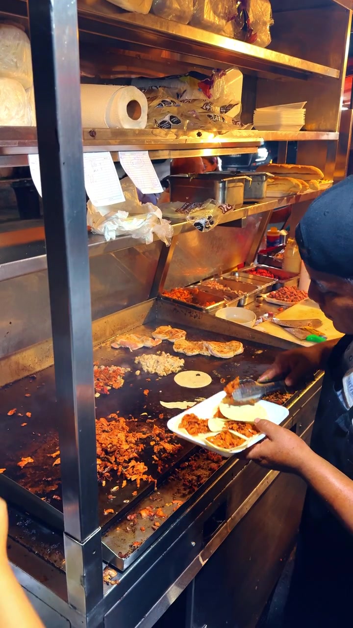 Tulum, Mexico, 1 August 2025: Variety of meats cooking on large commercial griddle outdoor. Different types of grilled meat and tortillas on stainless steel plancha, kitchen tools, street food setup.