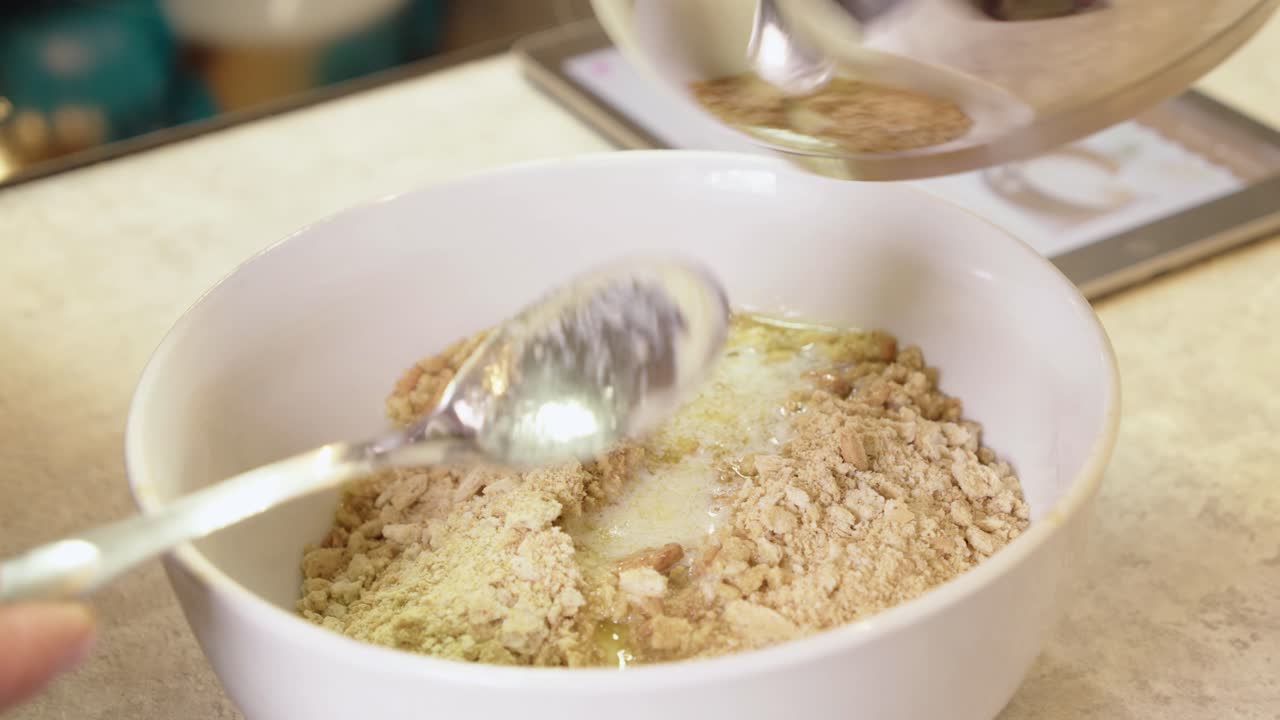 Melted butter is poured into dry crumble to make cheesecake crust