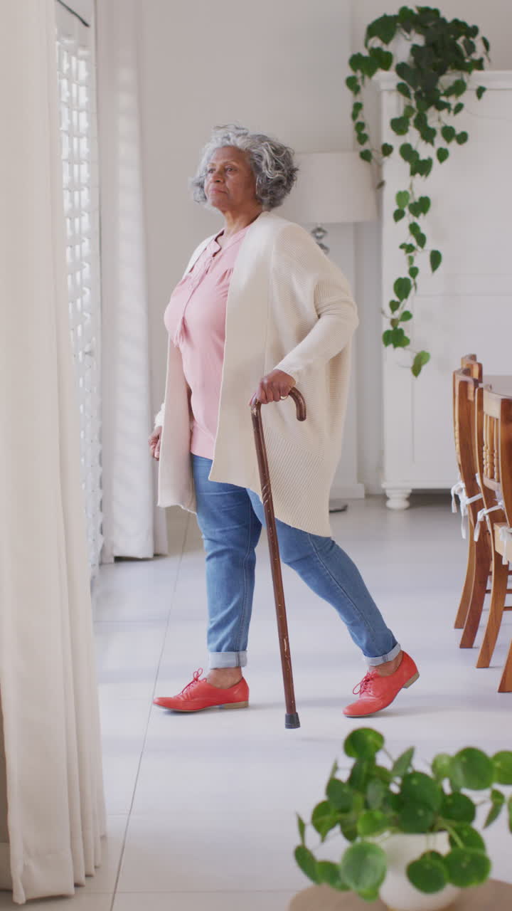 산책 지이를 들고 창문을 통해 바라보는 행복한 노인 아프리카계 미국인의 수직 비디오