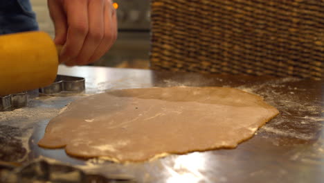 aplanar la masa de pan de jengibre con un rodillo sobre una mesa enharinada