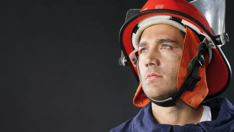 Thoughtful-fireman-standing-against-black-background-4K-4k