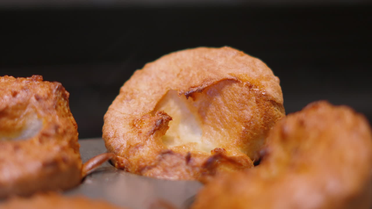 Tomada em recuo de Pudins Yorkshire britânicos dourados, crocantes e crescidos. Perfeito para comerciais de alimentos de alto padrão, promoções de assados de domingo britânicos e títulos de receitas de dar água na boca.