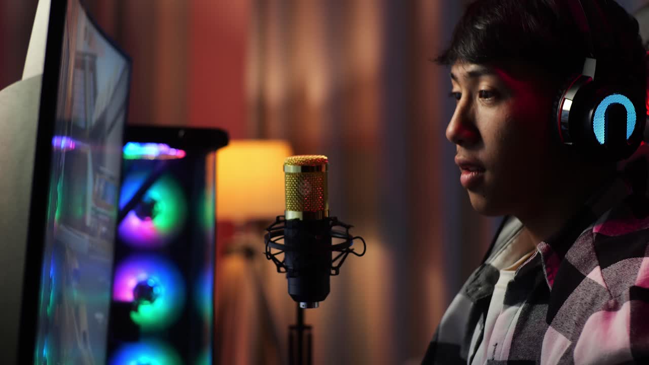 vista lateral de cerca de un niño asiático que grita gol y baila celebrando el juego ganador a través de la red en una computadora personal. videojuego de transmisión en vivo, escritorio iluminado por luz de tira led rgb