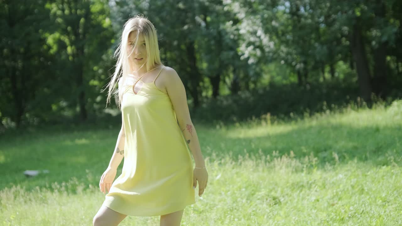 노란색 드레스를 입은 여자가 여름 공원에서 우아하게 춤을 춘다