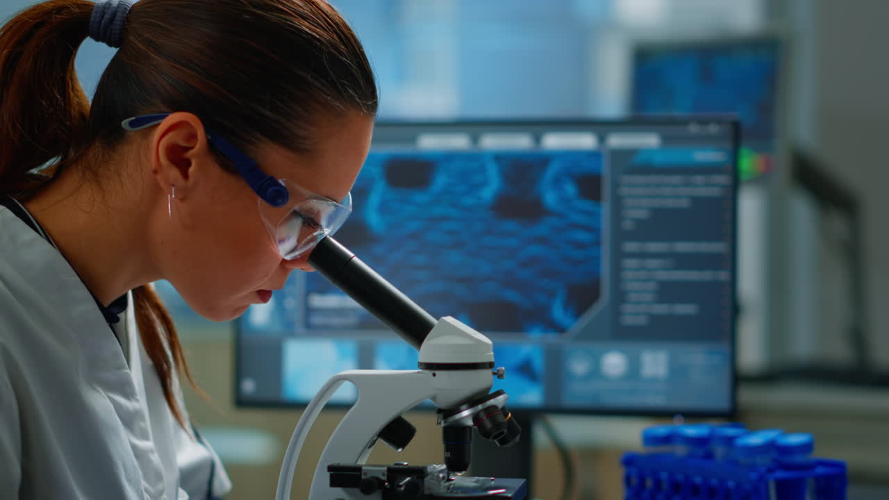 Portrait of scientist looking under microscope in medical lab