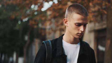 young student walking and using mobile phone outdoors.