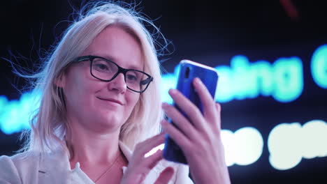 Portrait-Of-A-Business-Woman-With-A-Smartphone-Against-The-Background-Of-The-Ticker-With-The-News-An