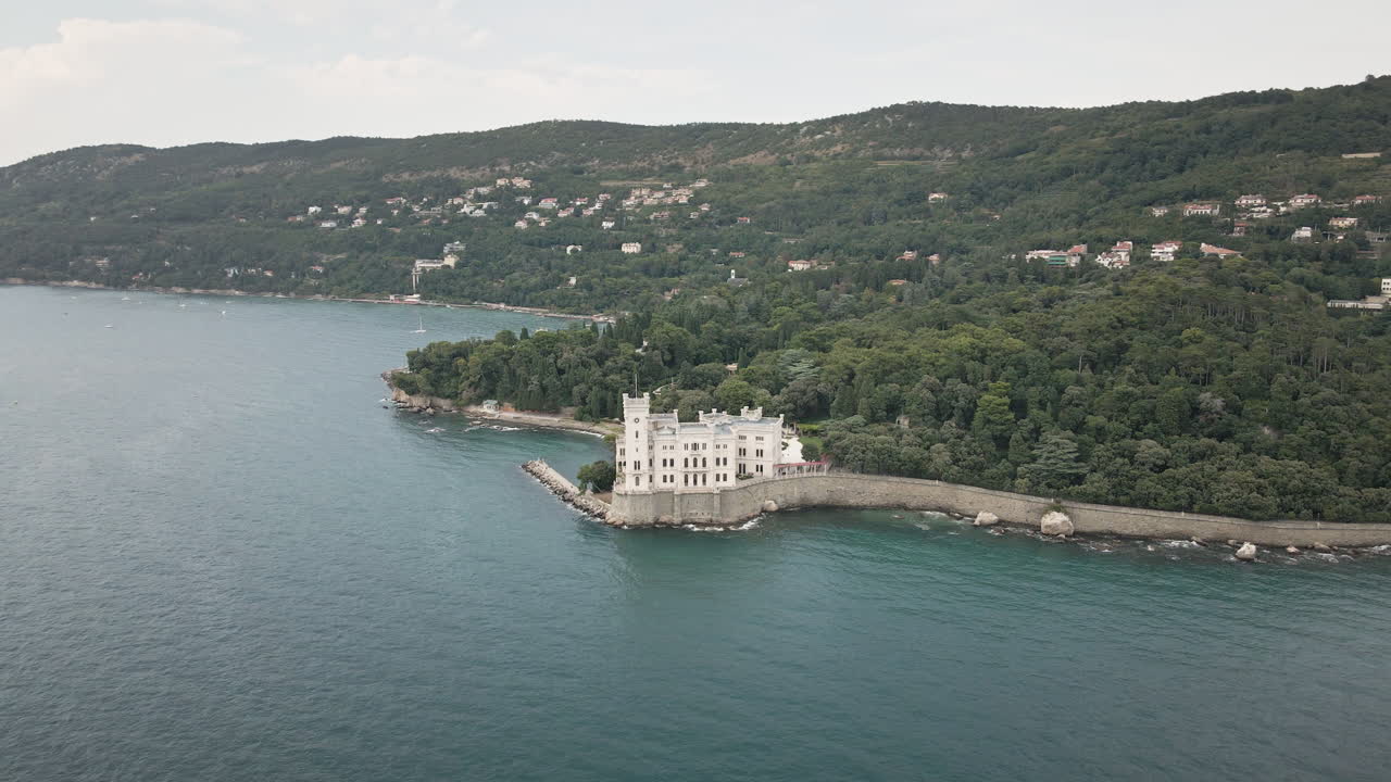 Valorizza la tua storia con un'orbita fluida di drone 4K UHD intorno al Castello di Miramare sul Golfo di Trieste, Italia, rivelando pareti rocciose e il mare color verde acqua per promozioni