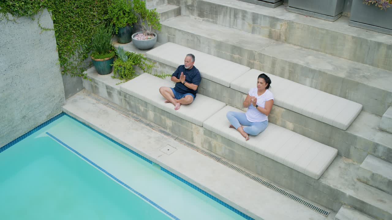 African American pair sitting poolside pullback starting, stretching into meditation, copy space
