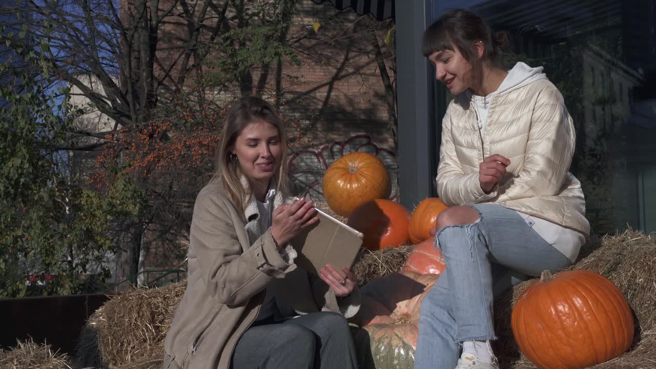두 명의 여성이 호박으로 둘러싸인 태블릿에 대해 논의하고 있습니다.