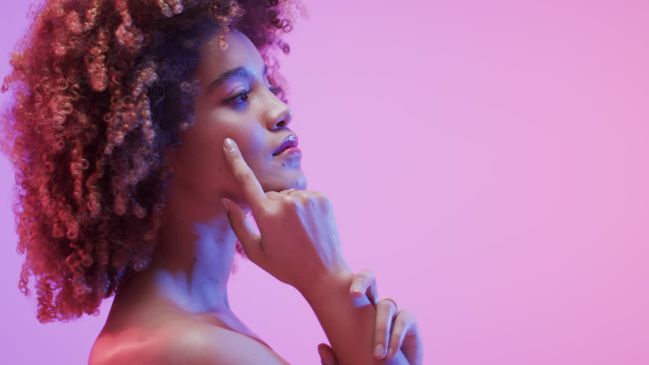 Femme biraciale aux cheveux foncés dans une lumière bleue et rose avec espace de copie, au ralenti