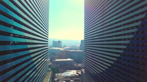 the drone flies between two buildings with glass windows.