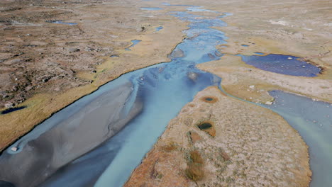 beautiful total view tracking shot of a river, that flows through a stony and barren landscape, sunny day, daylight, no people