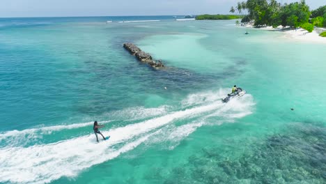 drone tracking shot over man riding a jet ski at tropical paradise exotic island with blue and turquoise ocean sea view. adventure concept for tourist attraction at beach vacation sport at summer day