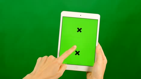 mujer de negocios usando una tableta de pantalla verde en blanco sobre un fondo verde.
