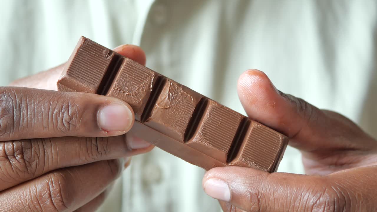 persona que sostiene una barra de chocolate rota