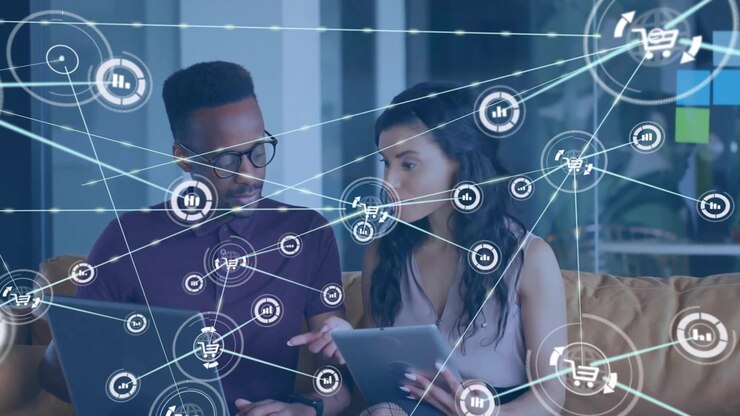 Animation of connected icons over diverse coworkers discussing reports on laptop in office