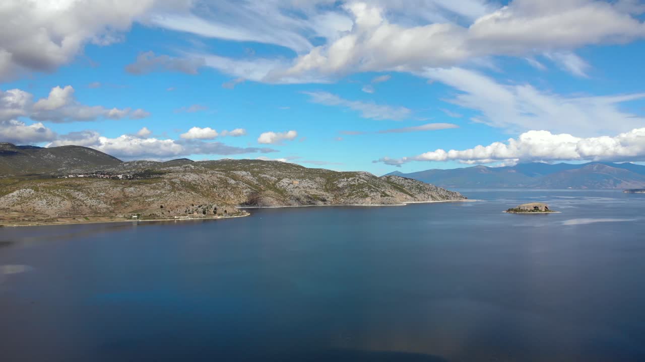 Beautiful landscape with mountain lake and white clouds on blue sky in Prespa, Albania