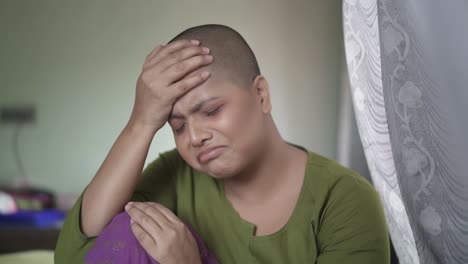 worried and hopeless cancer patient bald asian girl is sad and crying at home, after chemotherapy