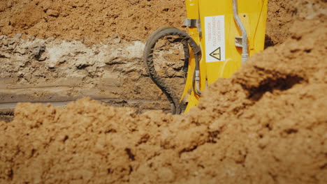 excavator bucket extracts ground from deep trench