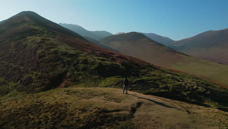 excursionista en la ladera con revelación de órbita de misty mountains y green valley con destello de lente natural en barrow cayó english lake district uk