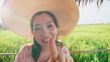 Asiatische-Frau-Mit-Hut-Zeigt-Per-Videoanruf-Ein-Reisfeld-Mit-Einem-Glücklichen-Tag-Im-Sommer