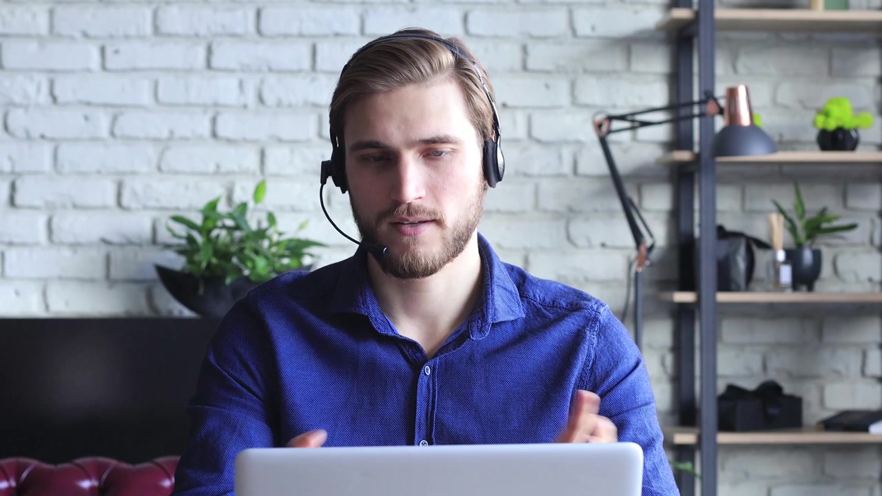 Young Man with Headset Talking on Video Call in Home Office