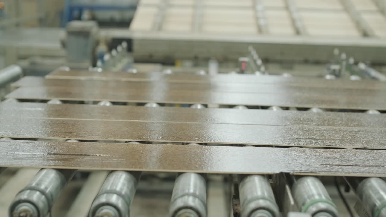 Assi di legno che si muovono su un nastro trasportatore automatizzato in fabbrica.