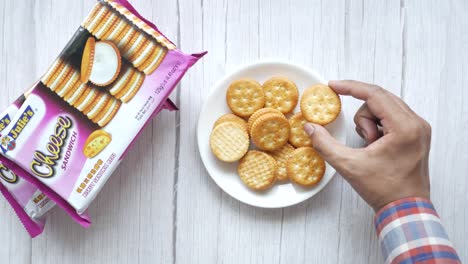 recogiendo a mano una galleta de sándwich de queso de julie