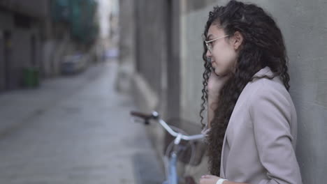 young woman leaning against a wall in a city street