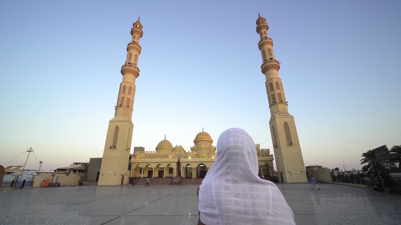 mujer con hijab disfrutando del amanecer, puesta de sol vista de la mezquita de el mina en hurghada, egipto y orando